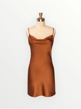 Rust-colored satin slip dress features a cowl neckline and spaghetti straps